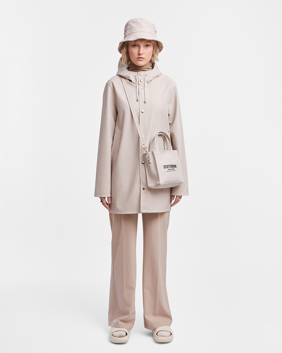 A woman with a Raincoat in color light sandl by Stutterheim